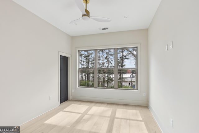 unfurnished room with baseboards, visible vents, light wood-style flooring, and a ceiling fan