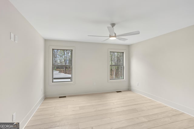 spare room featuring baseboards, light wood-style flooring, ceiling fan, and visible vents