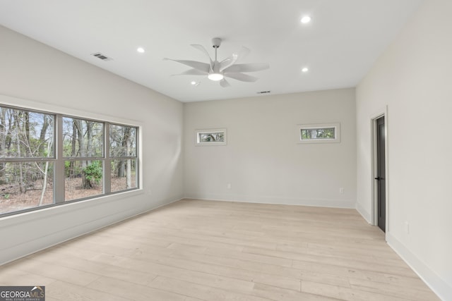 unfurnished room featuring a wealth of natural light, visible vents, light wood-style floors, and a ceiling fan
