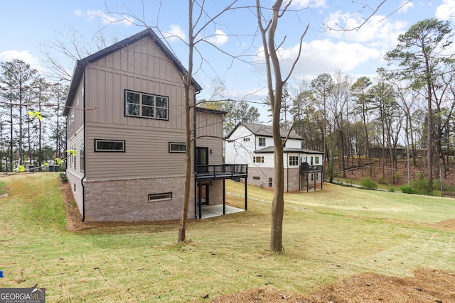 back of house with a wooden deck, board and batten siding, and a yard