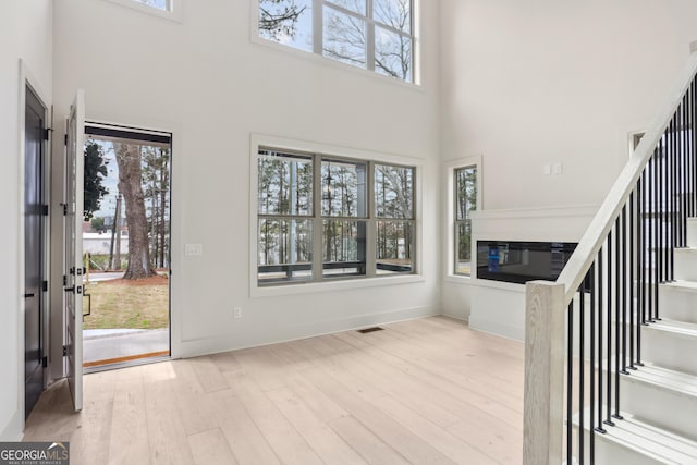 foyer entrance with a high ceiling, a wealth of natural light, and wood finished floors