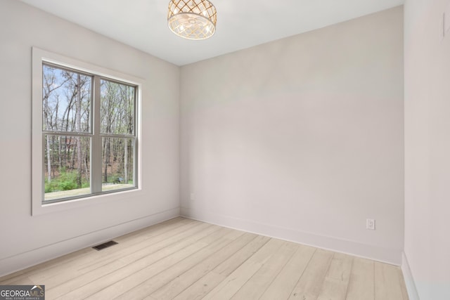 spare room featuring baseboards, visible vents, and light wood-style floors