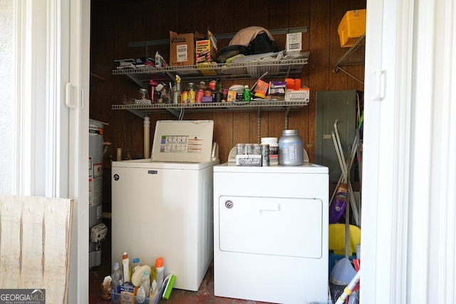 clothes washing area featuring independent washer and dryer, wooden walls, and laundry area