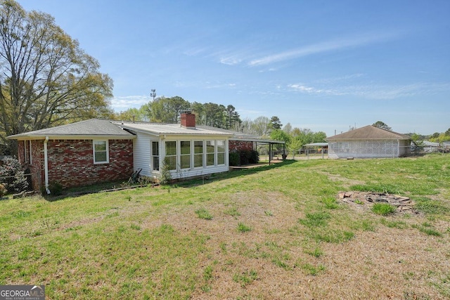 rear view of property with a lawn, a chimney, fence, and brick siding