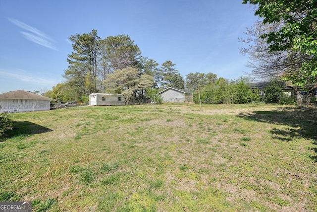 view of yard featuring an outbuilding, a storage unit, and fence