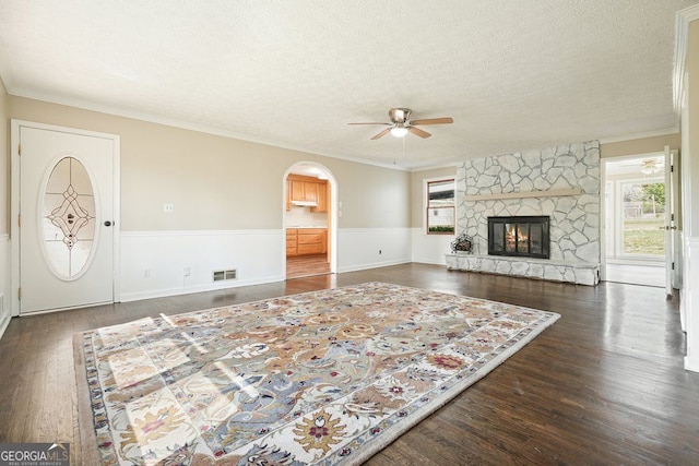 living room with crown molding, a textured ceiling, visible vents, a ceiling fan, and wood finished floors
