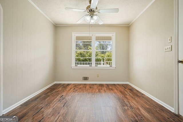 empty room featuring visible vents, wood finished floors, ornamental molding, and a ceiling fan
