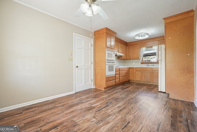 kitchen with light countertops, a sink, a ceiling fan, white appliances, and dark wood-style flooring