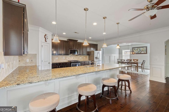 kitchen featuring dark brown cabinetry, a sink, crown molding, and appliances with stainless steel finishes