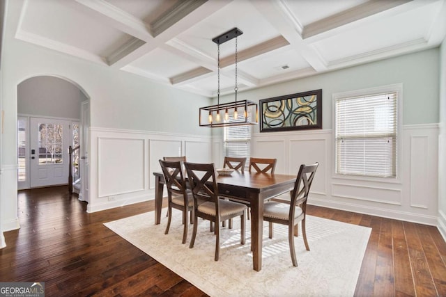 dining space featuring beamed ceiling, arched walkways, coffered ceiling, and dark wood-style floors