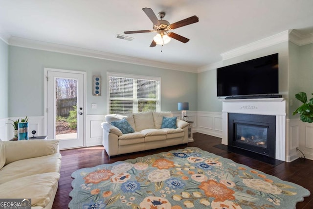 living area featuring plenty of natural light, visible vents, crown molding, and ceiling fan