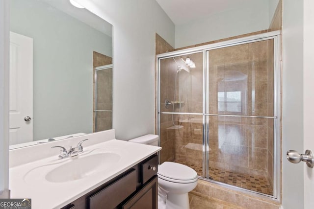 bathroom with a shower stall, vanity, tile patterned flooring, and toilet
