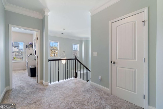 hall with baseboards, ornamental molding, an upstairs landing, and carpet floors