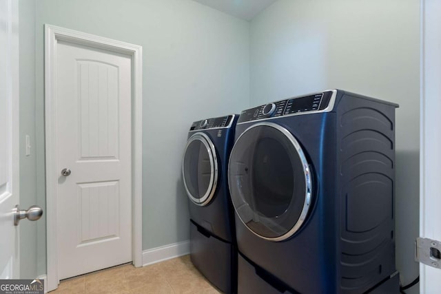 laundry area with washing machine and dryer, laundry area, baseboards, and light tile patterned flooring