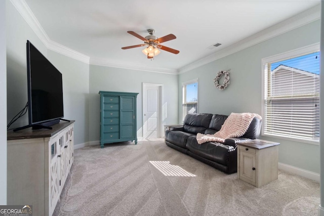 living area with ornamental molding, ceiling fan, light colored carpet, and baseboards