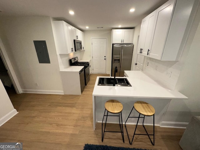 1735 Derry Ave SW, Atlanta, GA 30310 - kitchen with electric panel, a sink, light wood finished floors, a peninsula, and stainless steel appliances