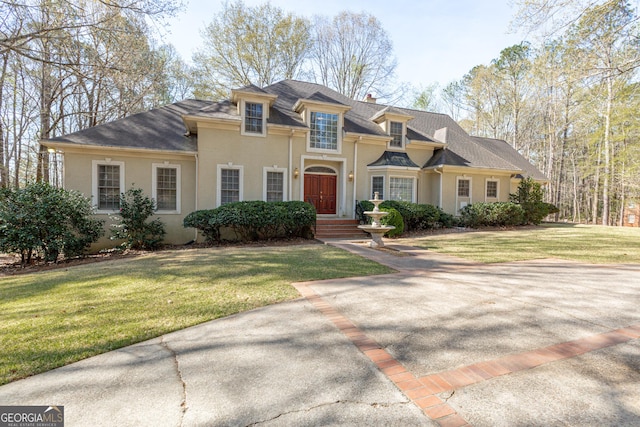 115 Flagstop Run, Fayetteville, GA 30215 - view of front facade with stucco siding, a front yard, a chimney, and roof with shingles