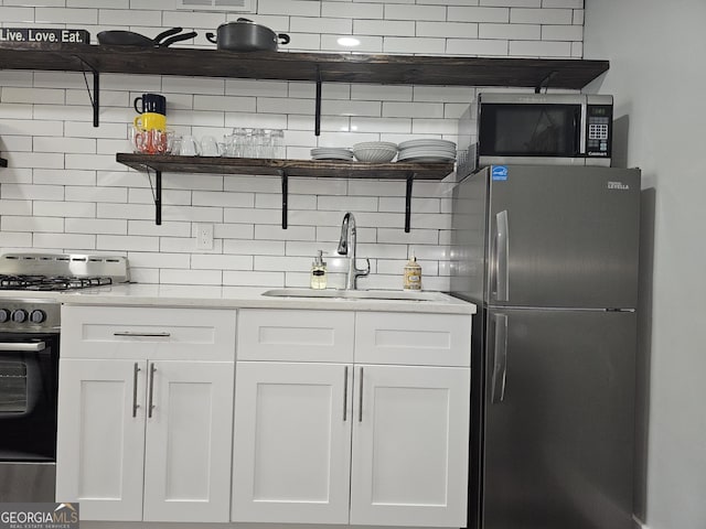 215 Piedmont Ave NE Unit 304, Atlanta, GA 30308 - kitchen featuring white cabinets, a sink, tasteful backsplash, light countertops, and appliances with stainless steel finishes