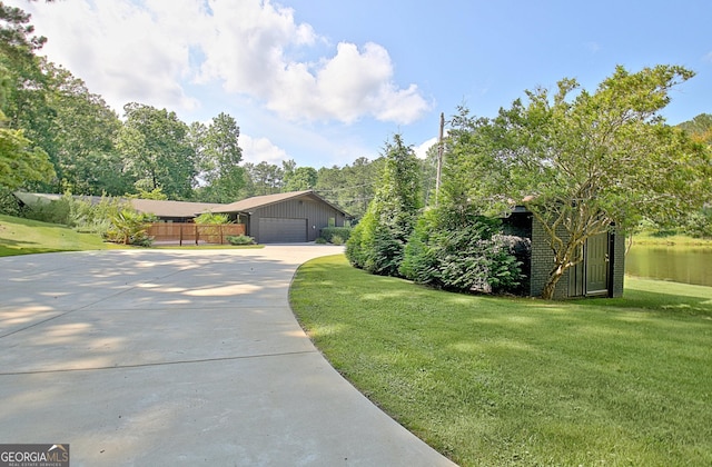 view of home's exterior with fence, an attached garage, driveway, an outbuilding, and a yard