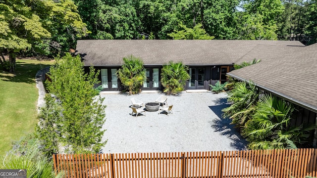 view of front of property with an outdoor fire pit, french doors, and roof with shingles