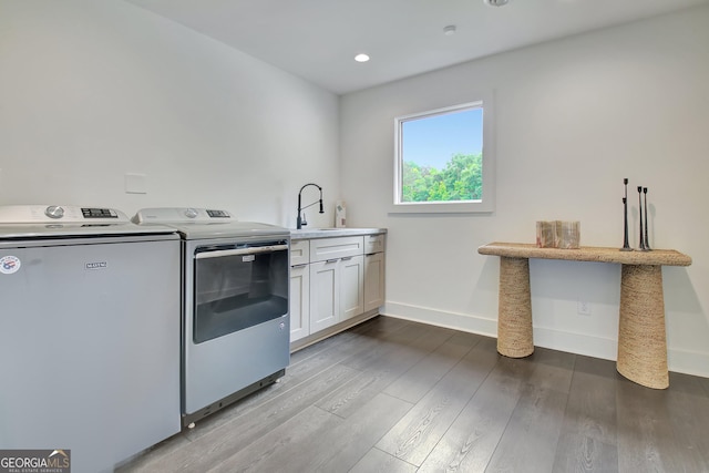 clothes washing area with washer and clothes dryer, baseboards, a sink, cabinet space, and wood finished floors