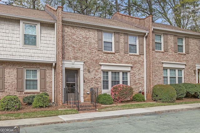 townhome / multi-family property featuring brick siding and roof with shingles