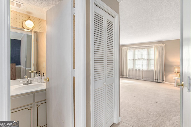 bathroom with baseboards, a textured ceiling, visible vents, and vanity
