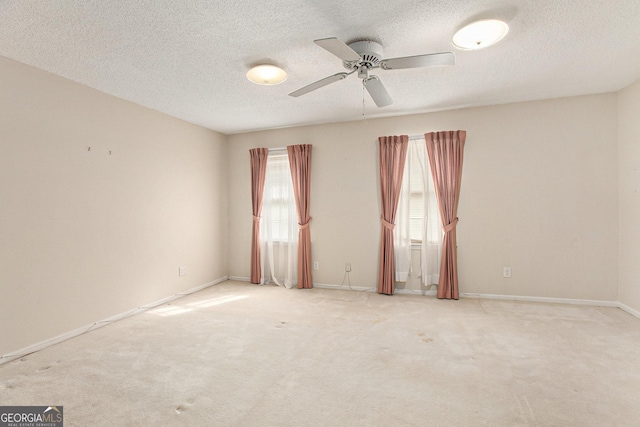 spare room with a textured ceiling, carpet, and a ceiling fan