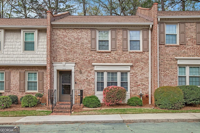 townhome / multi-family property with brick siding and roof with shingles