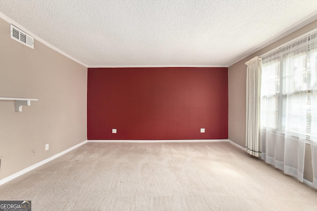 spare room featuring ornamental molding, baseboards, light colored carpet, and visible vents