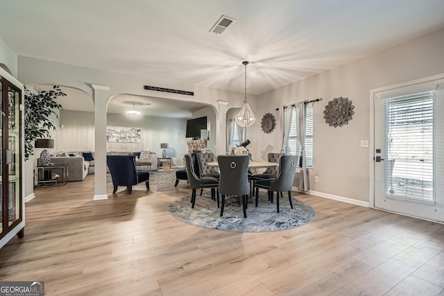 dining space with arched walkways, wood finished floors, visible vents, and baseboards