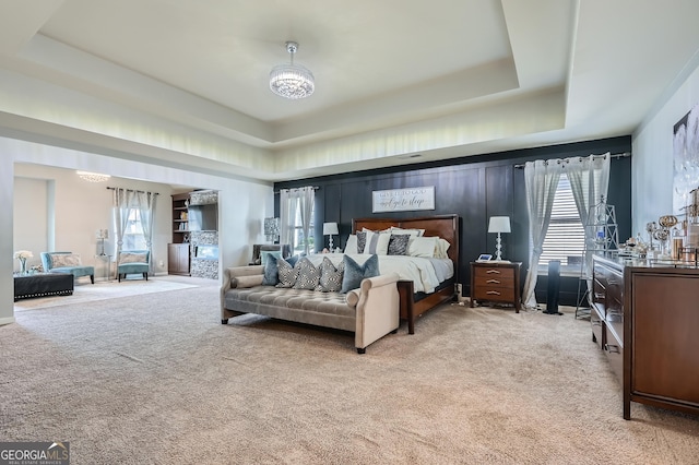 bedroom featuring a raised ceiling, light carpet, and an inviting chandelier