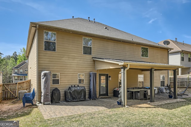 rear view of property with a yard, a patio area, central AC, and fence
