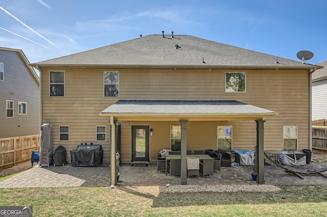 rear view of property featuring fence, a patio area, a shingled roof, and an outdoor living space
