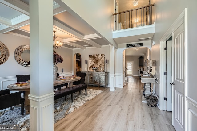 foyer featuring arched walkways, visible vents, coffered ceiling, beamed ceiling, and wood finished floors
