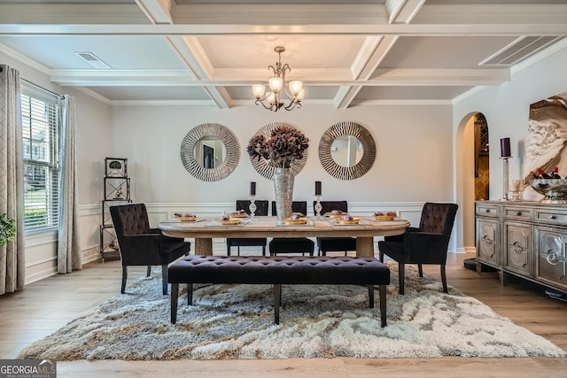 dining area featuring wood finished floors, arched walkways, an inviting chandelier, beamed ceiling, and coffered ceiling