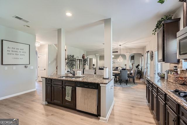 kitchen with light stone counters, visible vents, a sink, arched walkways, and appliances with stainless steel finishes