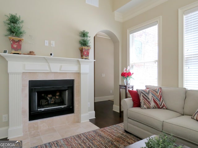 living room with a tiled fireplace, visible vents, arched walkways, and a wealth of natural light