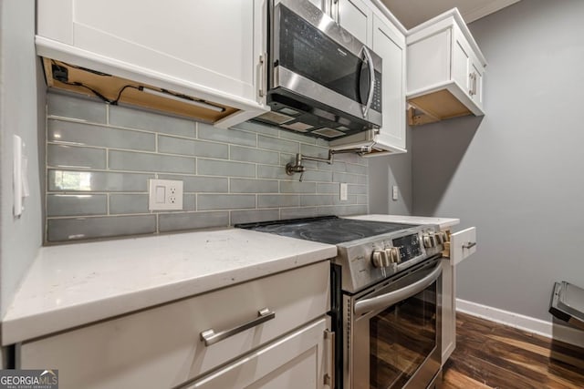 2921 Lenox Rd NE Unit 113, Atlanta, GA 30324 - kitchen featuring stainless steel appliances, light stone countertops, dark wood-style flooring, white cabinets, and tasteful backsplash
