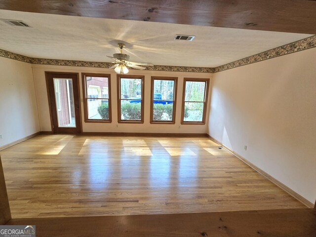 spare room with baseboards, light wood-style flooring, visible vents, and ceiling fan