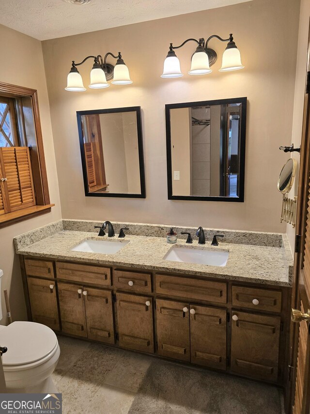 bathroom featuring double vanity, toilet, and a sink