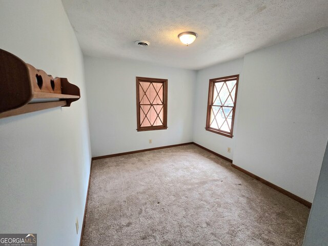 unfurnished room featuring baseboards, carpet flooring, a textured ceiling, and visible vents