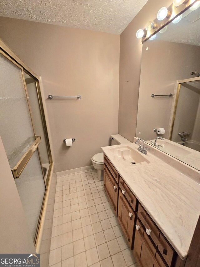 full bathroom featuring vanity, toilet, a shower with door, a textured ceiling, and tile patterned floors