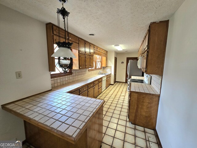 kitchen featuring backsplash, tile counters, and white appliances