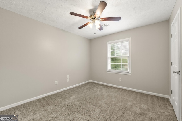 carpeted spare room featuring baseboards, a textured ceiling, and a ceiling fan