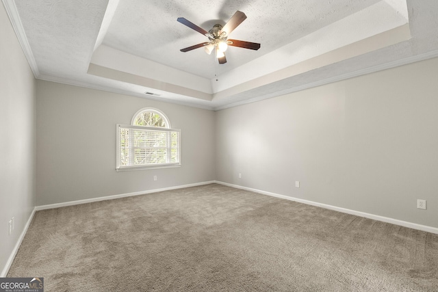 carpeted spare room featuring a textured ceiling, visible vents, baseboards, a ceiling fan, and a tray ceiling
