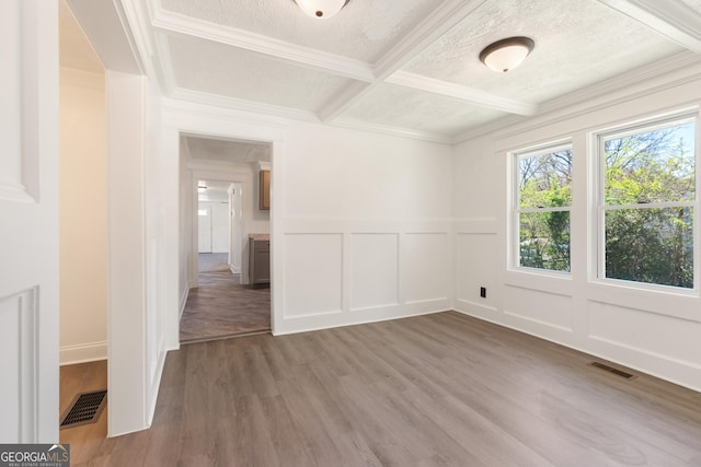 spare room with a textured ceiling, visible vents, a decorative wall, and wood finished floors