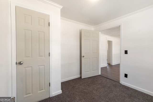 unfurnished bedroom featuring crown molding, dark colored carpet, and baseboards