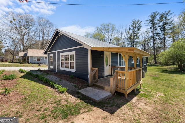 view of front of house with metal roof and a front lawn
