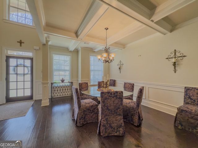 dining space with plenty of natural light, a decorative wall, beam ceiling, and dark wood-type flooring